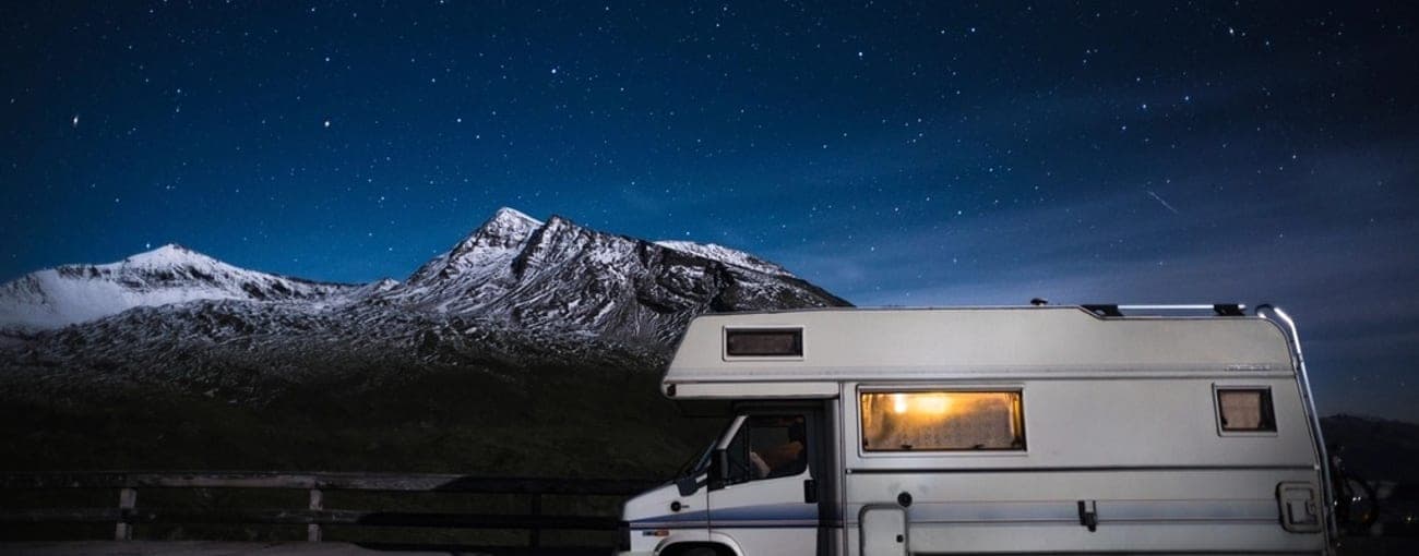 Camper parcheggiato di notte ai piedi di una montagna innevata